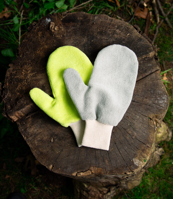 Two colorful mittens placed on a tree stump.